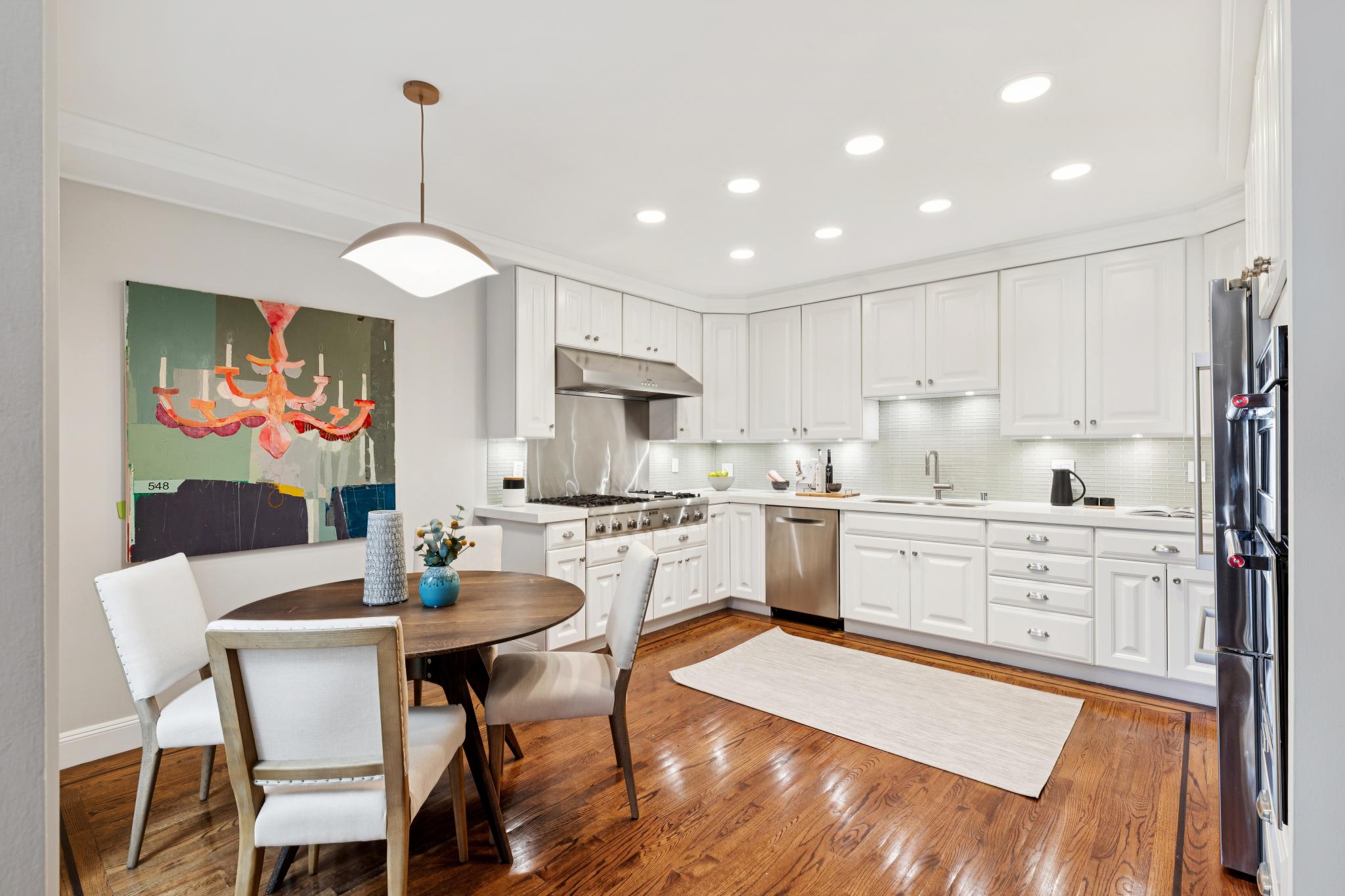 Kitchen and breakfast area with white cabinetry and sage green backsplash