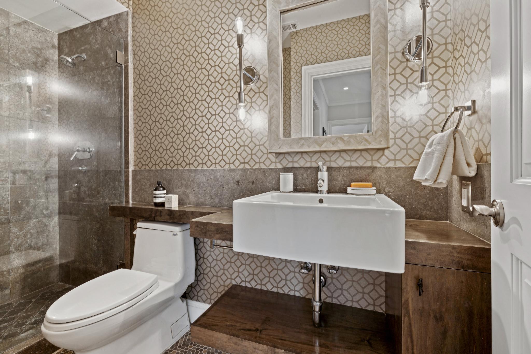 Lower-level bathroom with vessel sink and geometric wallpaper